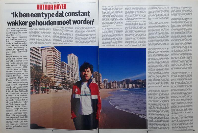 Stad aan de kust met hoge gebouwen en een man op het strand, onder een heldere blauwe hemel.