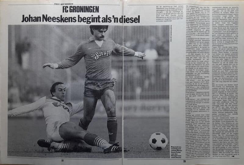 Johan Neeskens speelt voetbal, met een tegenstander die op de grond ligt, op een grasveld.