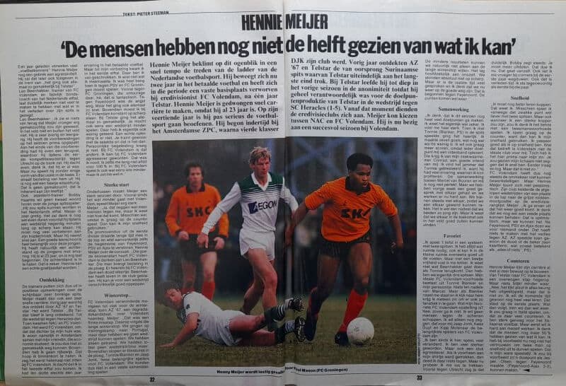 Spelers in een spannende voetbalwedstrijd, één speler valt, anderen rennen achter de bal aan.