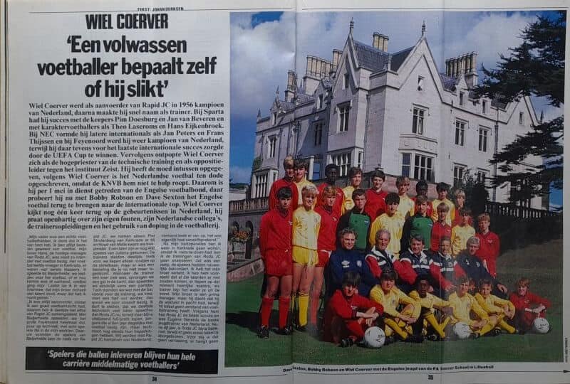 Voetbalteam met jonge spelers en coaches voor een groepsfoto buiten het clubhuis.