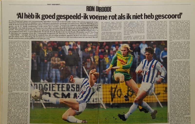 Voetbalwedstrijd met spelers in actie, inclusief een speler die de bal probeert te winnen.