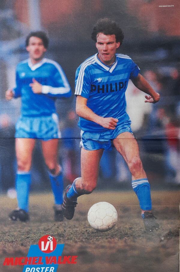 Voetbalspelers in blauwe uniforms tijdens een jeugdwedstrijd, met een jongen die de bal dribbelt op.