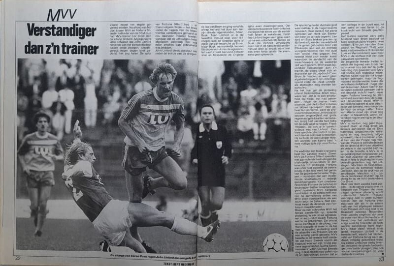 Voetbalwedstrijd met spelers in actie, inclusief een sliding tackle en een scheidsrechter op de acht.