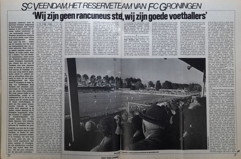 Gezicht op een voetbalwedstrijd met publiek en spelers op het veld.