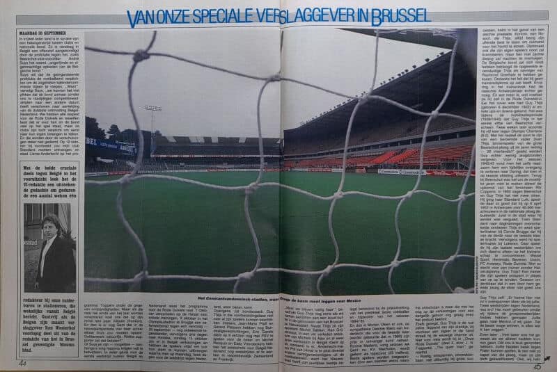 Leeg voetbalstadion gezien door het doelnet, onder een bewolkte hemel.