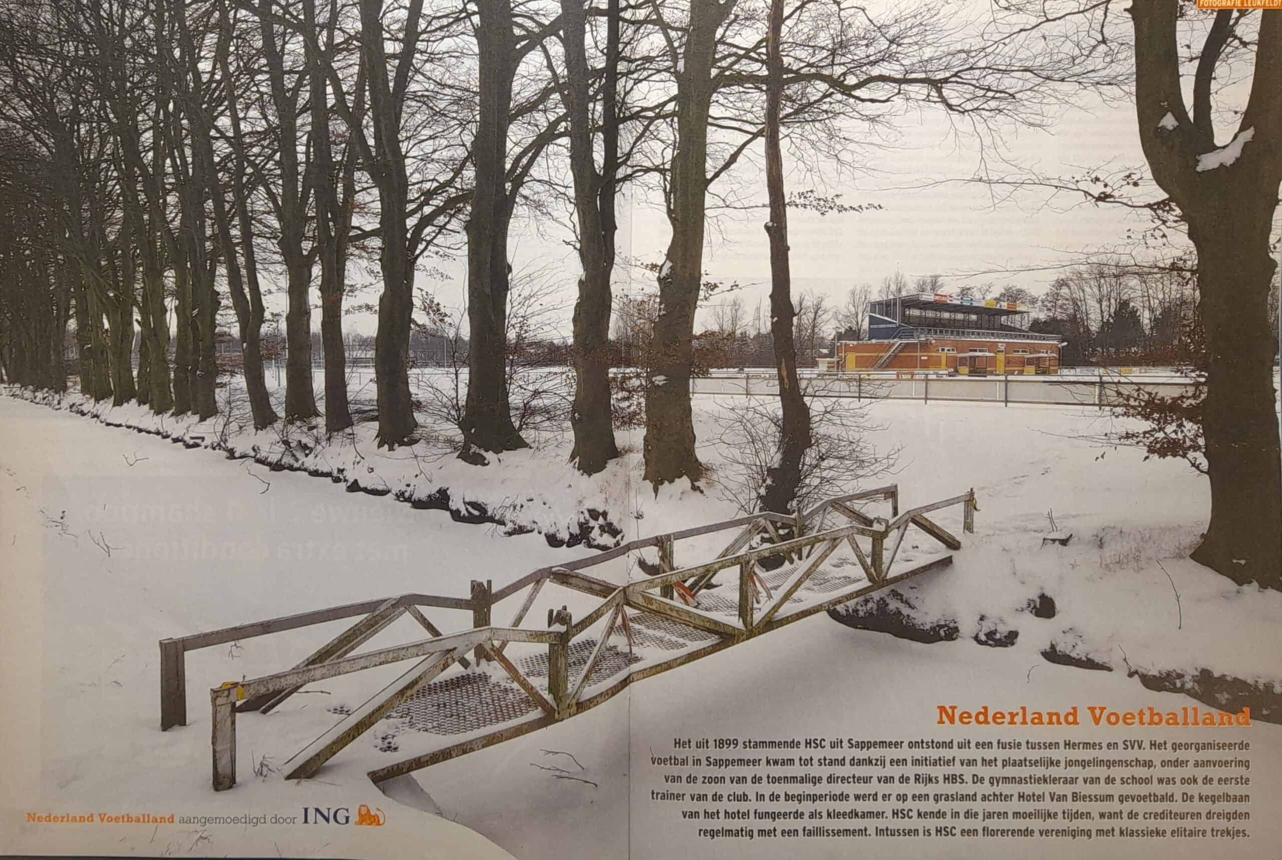 Sneeuwbedekt voetbalveld met kapotte toegangspoort in Groningen.