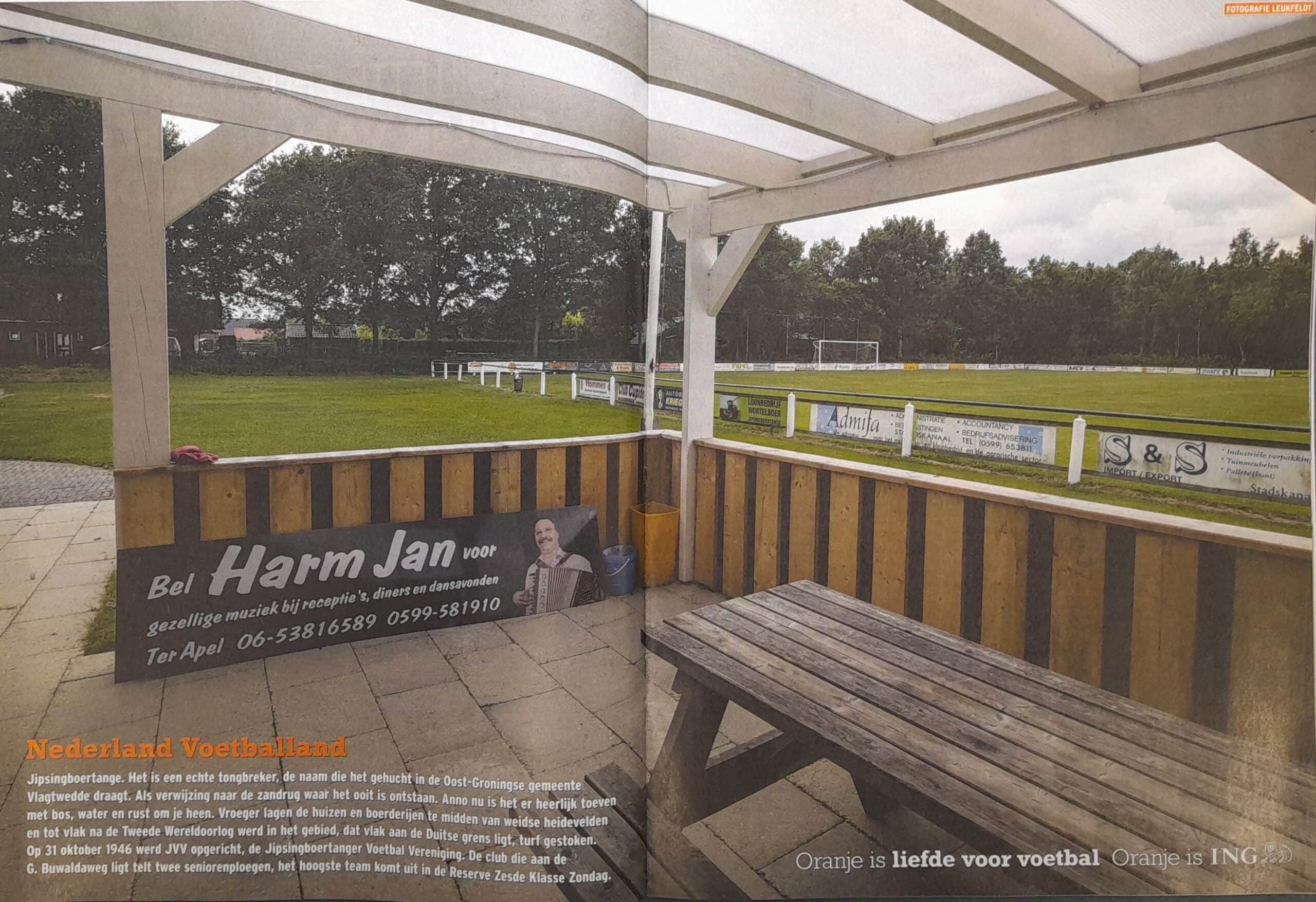 Voetbalveld in Groningen met tribune en omheining.
