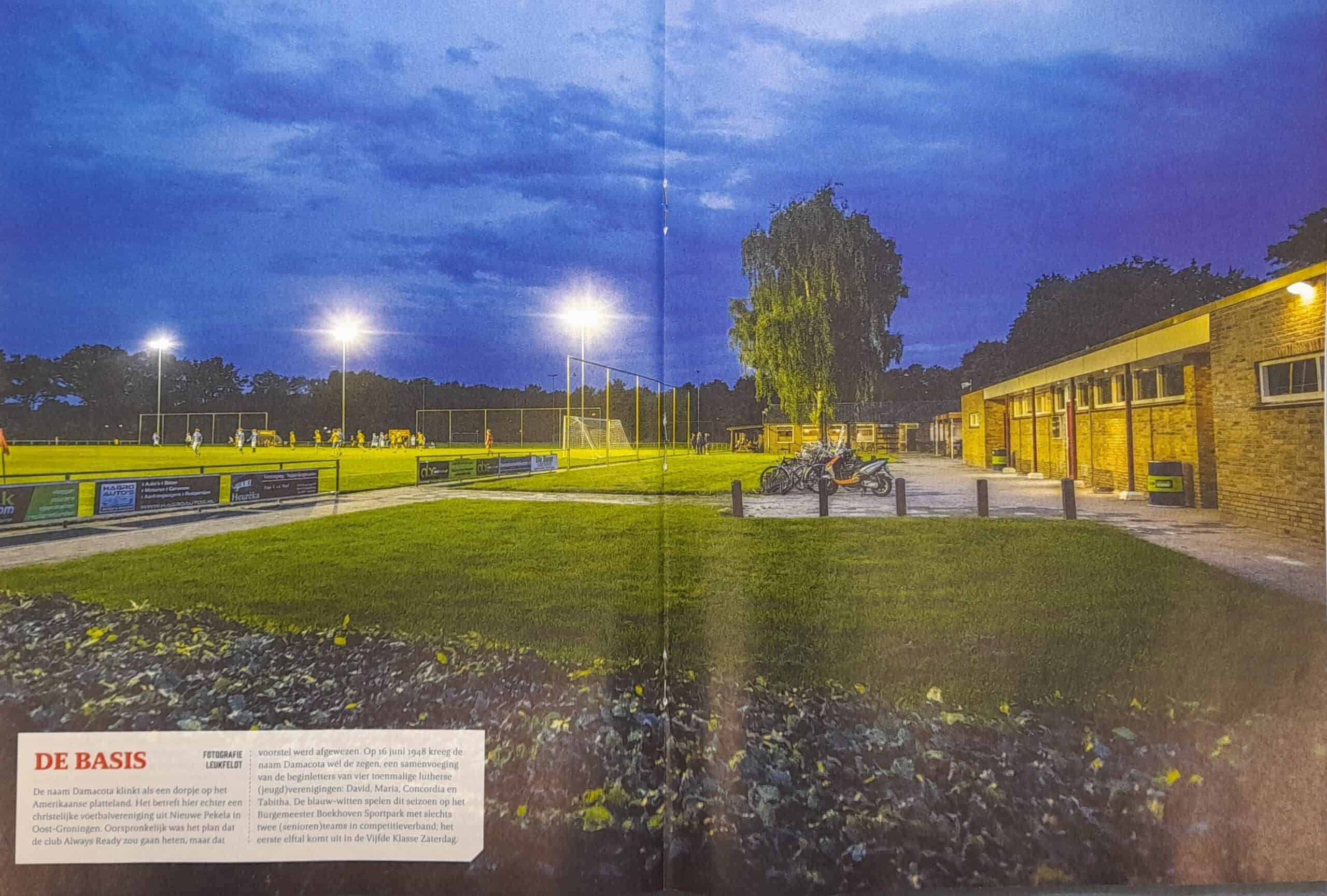 Verlicht amateurvoetbalveld in Groningen bij schemering.